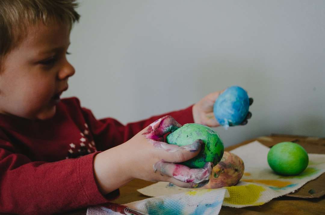chłopiec trzymający pomalowane na niebiesko i zielono skorupki jajek puzzle online