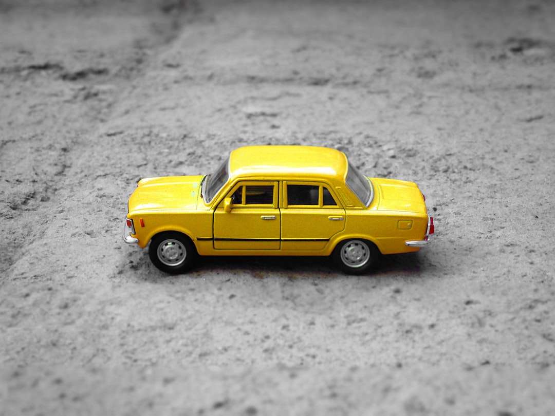 Żółty sedan odlewa na żwirze puzzle online