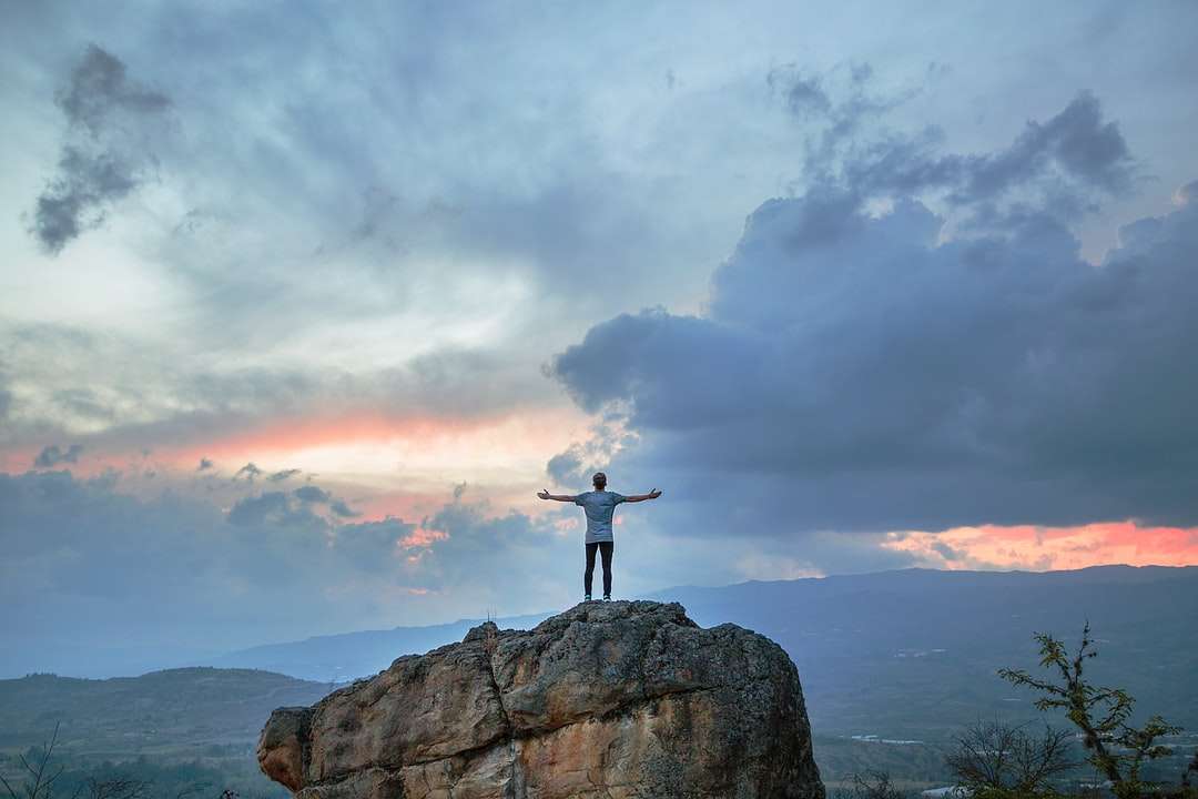 Człowiek stojący na szczycie góry górskiej podczas złotej godziny puzzle online