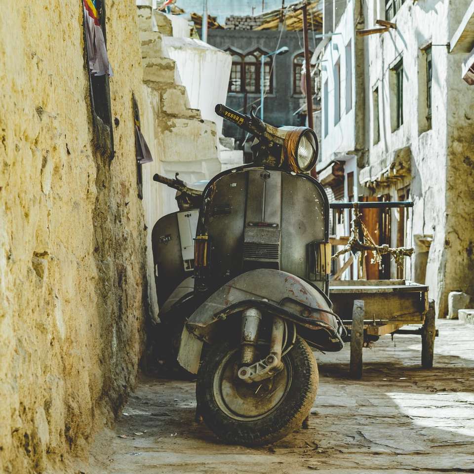 Szary skuter silnikowy zaparkowany obok brązowej ściany puzzle online
