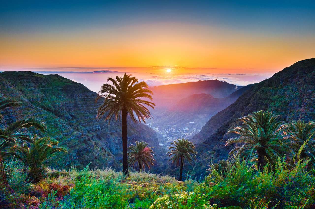Piękny widok niesamowita tropikalna sceneria z egzotycznymi palmami i górskimi dolinami nad szeroko otwarte morze w złotym wieczorowym świetle przy zmierzchem z niebieskim niebem i chmurami w lecie, Wyspy Kanaryjskie, Hiszpania puzzle online