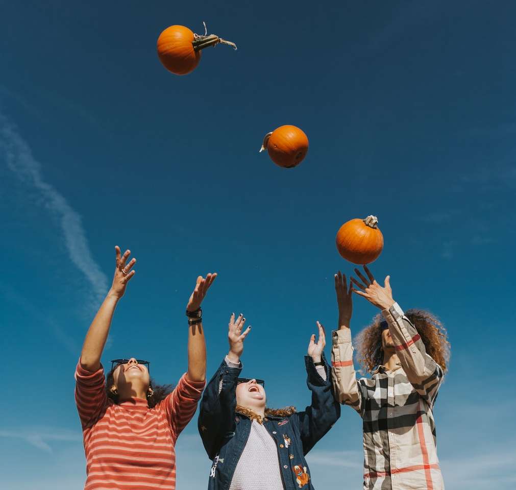 ludzie trzymający pomarańczową koszykówkę pod błękitnym niebem puzzle online