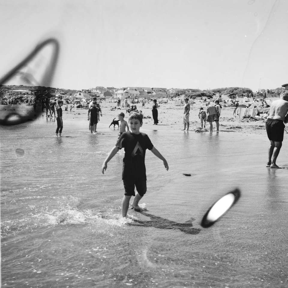 zdjęcie w skali szarości przedstawiające ludzi bawiących się na plaży puzzle online