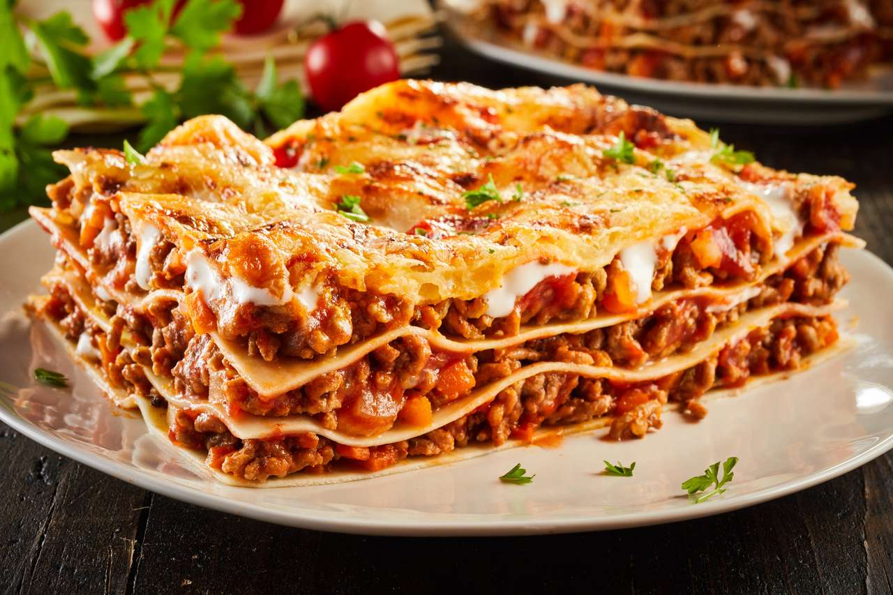 Część soczystej wołowiny ziemnej lasagne zwieńczone roztopionym serem i przyozdobionym świeżą pietruszką serwowaną na talerzu w widoku z bliska na menu puzzle online