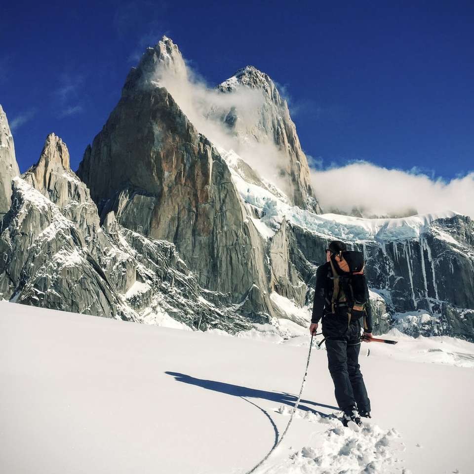 Osoba chodząca po śnieżnym polu blisko góry puzzle online