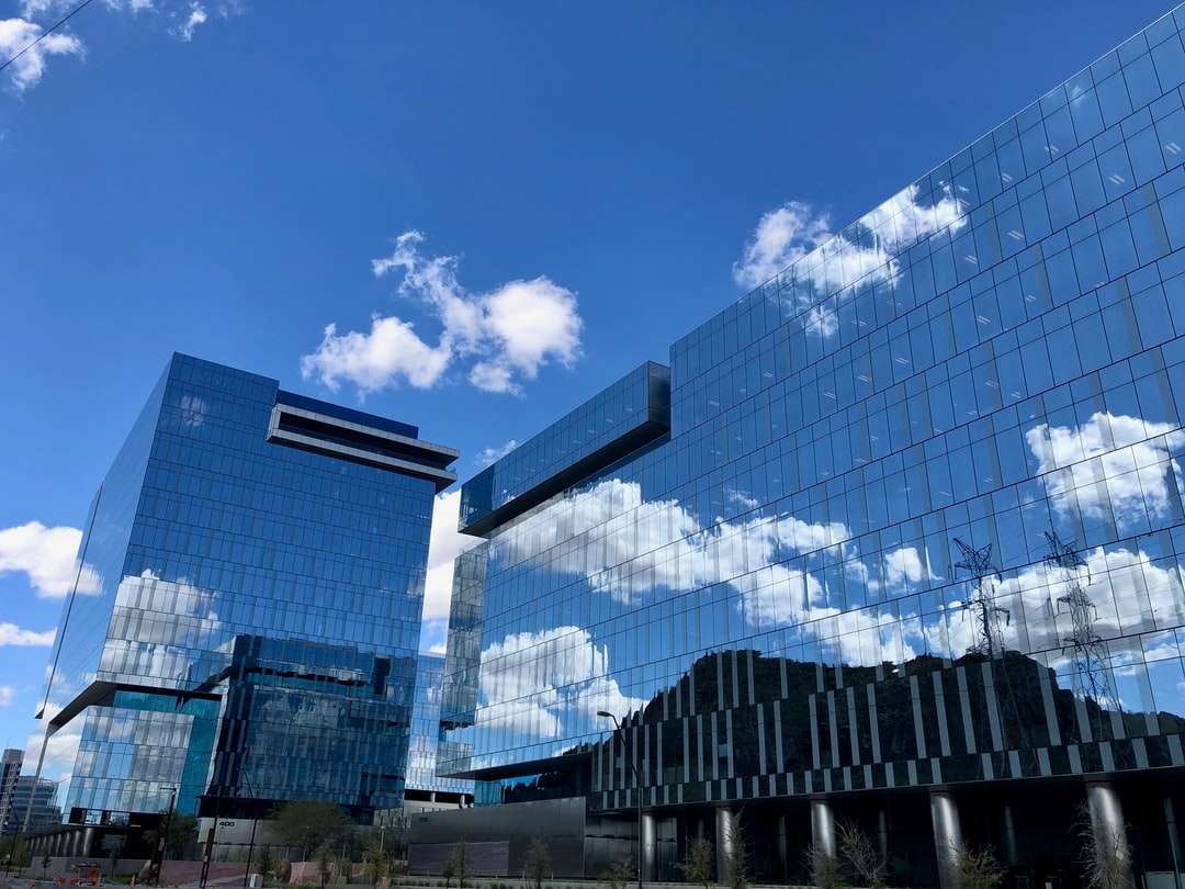 Niebieski i biały szklany budynek pod błękitnym niebem w ciągu dnia puzzle online