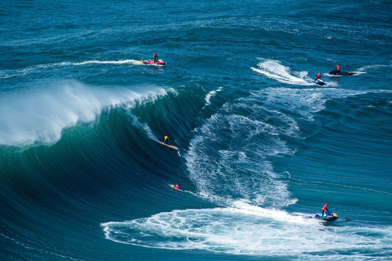 Surfingowcy płynie na Oceanie Atlantyckim w pobliżu Municipality Nazare w Portugalii puzzle online