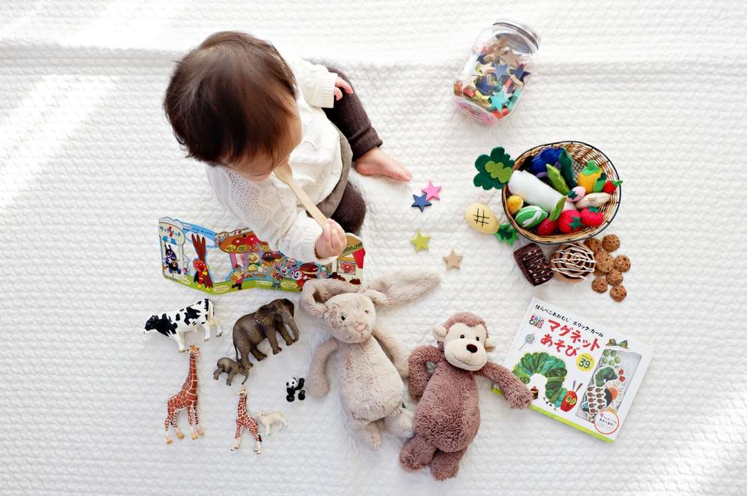 chłopiec siedzący na białym obrusie otoczony zabawkami puzzle online