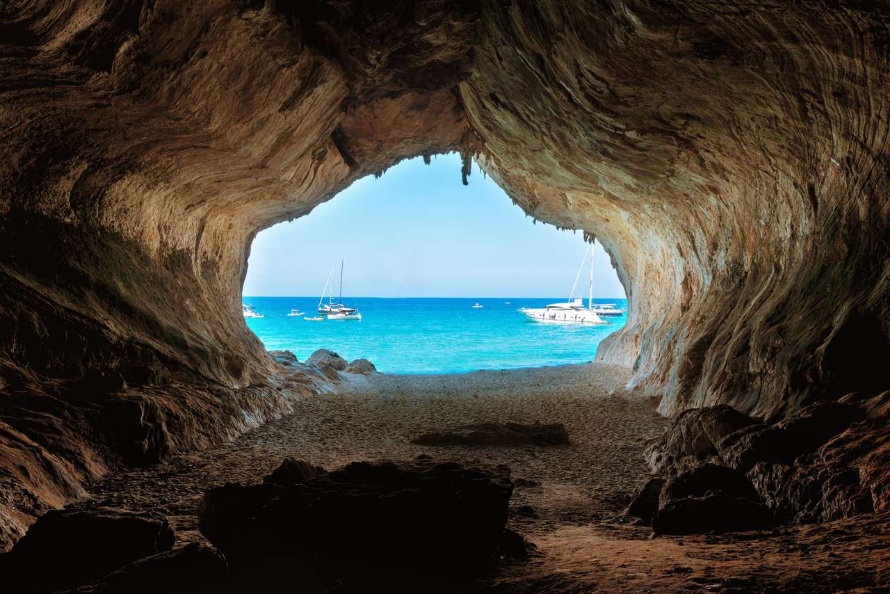 Widok z wnętrza dużej jaskini na plażę i błękitne morze. Śródziemnomorskie wybrzeże, Sardynia, Włochy. puzzle online