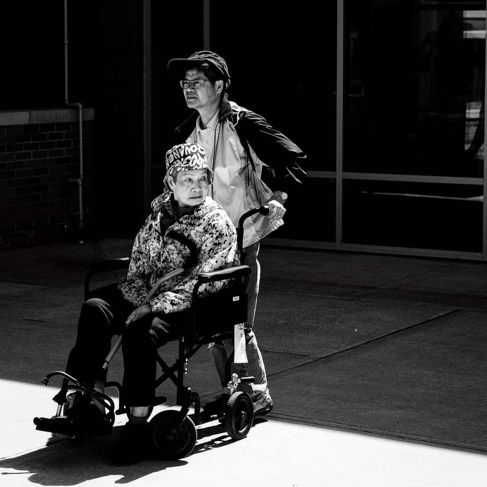 zdjęcie w skali szarości przedstawiające mężczyznę pchającego wózek inwalidzki puzzle online