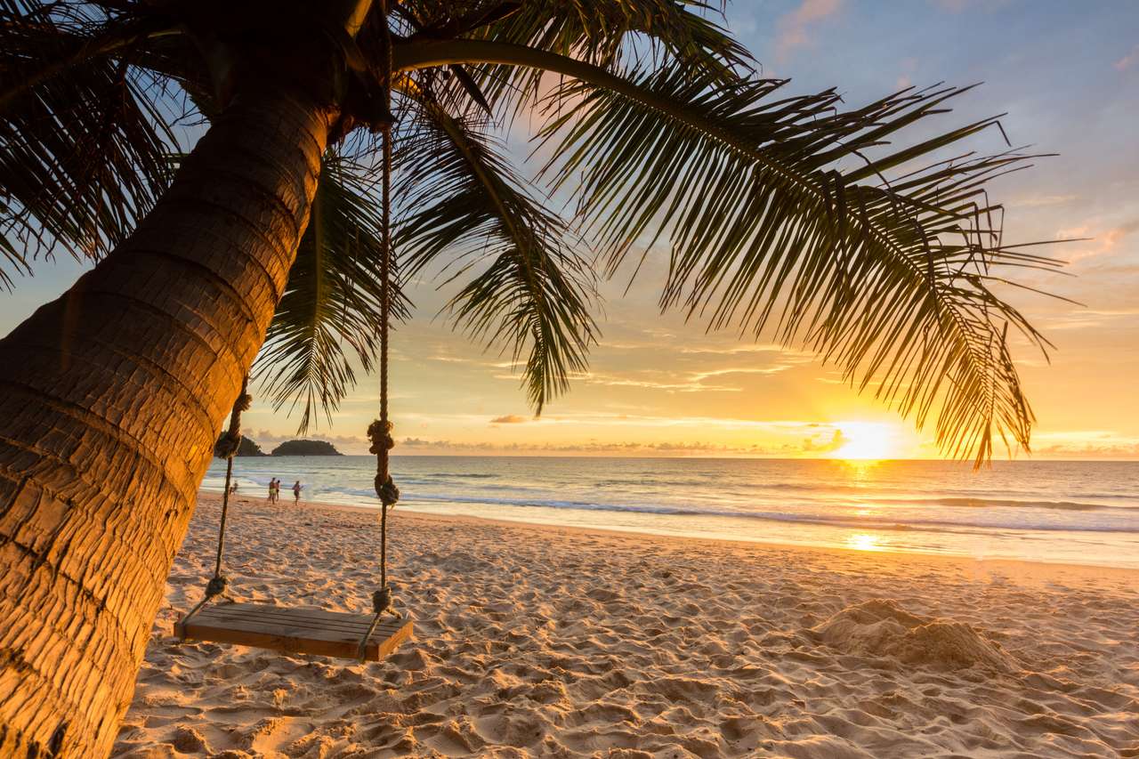 Drewniana huśtawka pod kokosowym drzewem na plaży z zmierzchowym tłem puzzle online