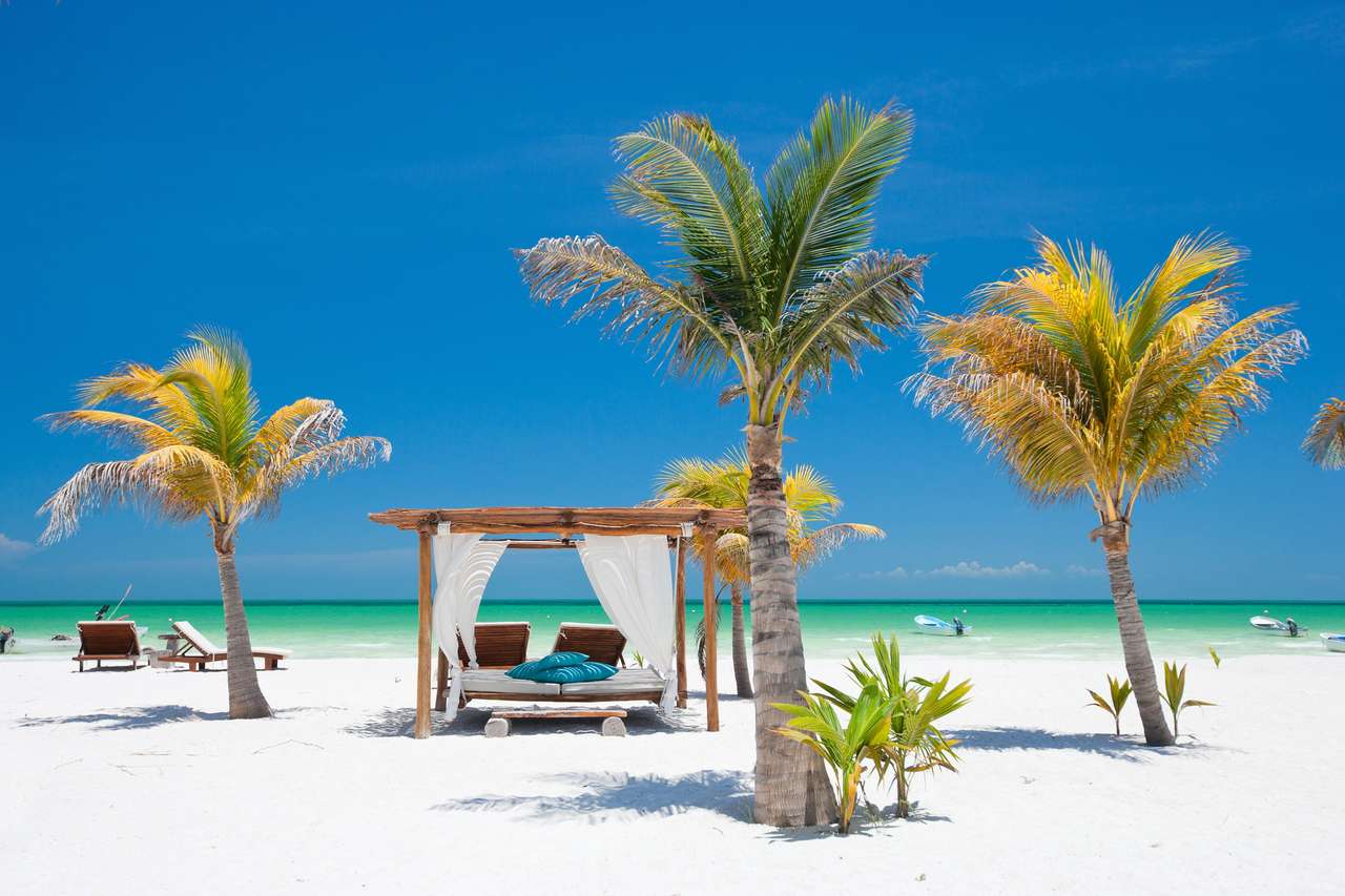 Łóżka na plaży wśród palmów na idealnym tropikalnym wybrzeżu puzzle online