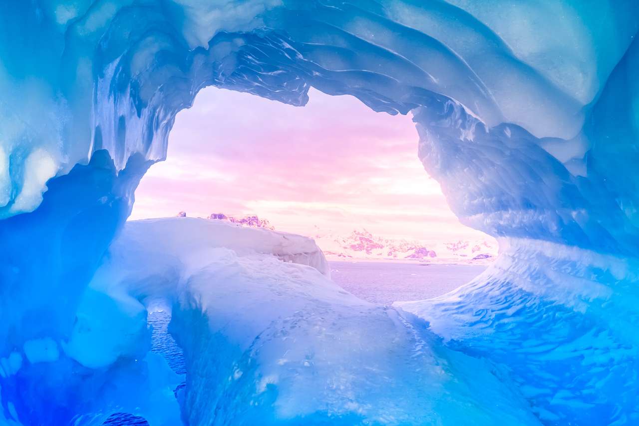 Grotta di ghiaccio blu ricoperta di neve e inondata di luce puzzle
