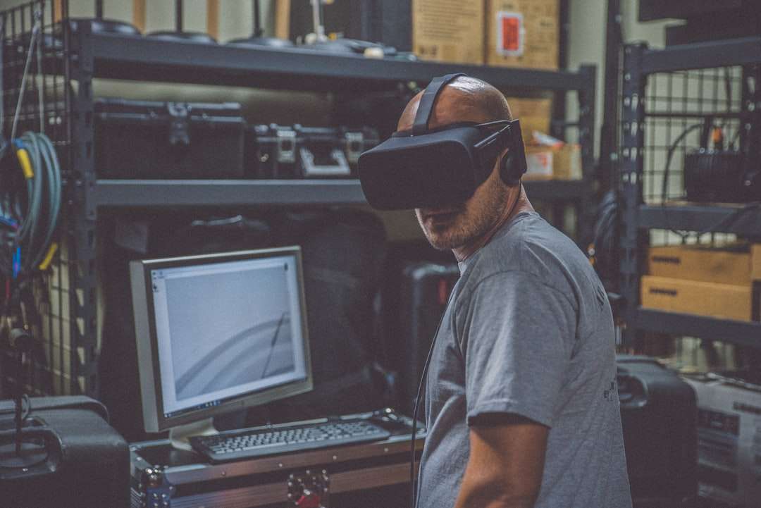 osoba korzystająca z czarnego zestawu słuchawkowego VR przed komputerem puzzle online
