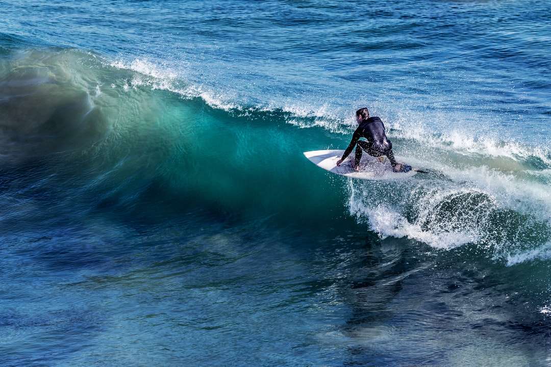 Osoba na białej desce surfingowej otoczonej niebieską wodą oceanową puzzle online