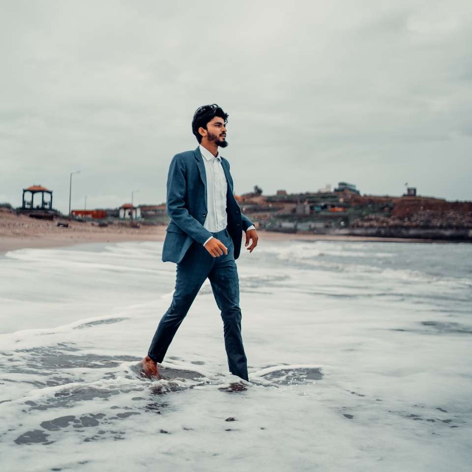 mężczyzna w niebieskiej kurtce dżinsowej stojący na plaży w ciągu dnia puzzle online