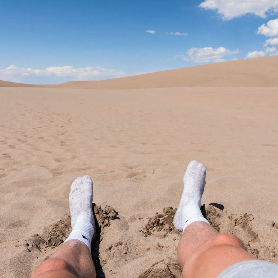 osoba w białych skarpetkach stojąca na brązowym piasku w ciągu dnia puzzle online