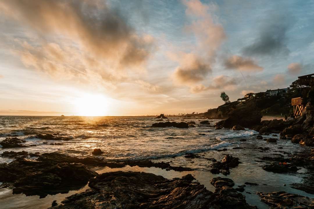 fale oceanu rozbijające się o skały podczas zachodu słońca puzzle online