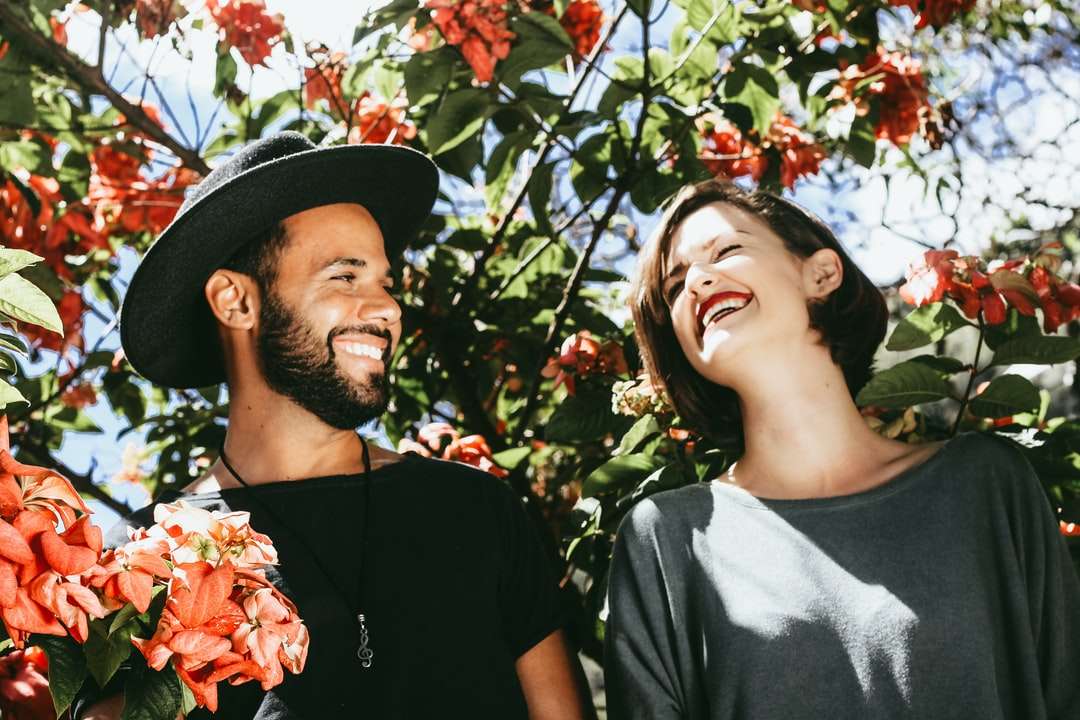mężczyzna i kobieta otoczeni czerwonymi i zielonymi drzewami kwiatowymi puzzle online