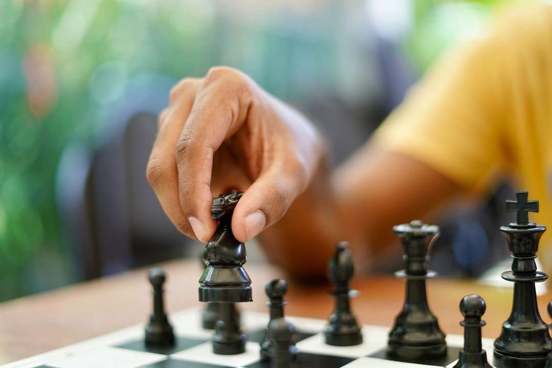 osoba trzymająca czarno-srebrny pionek szachowy puzzle online