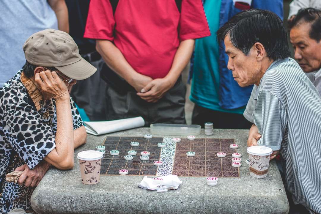 dwóch mężczyzn siedzących przy stole i grających w grę puzzle online