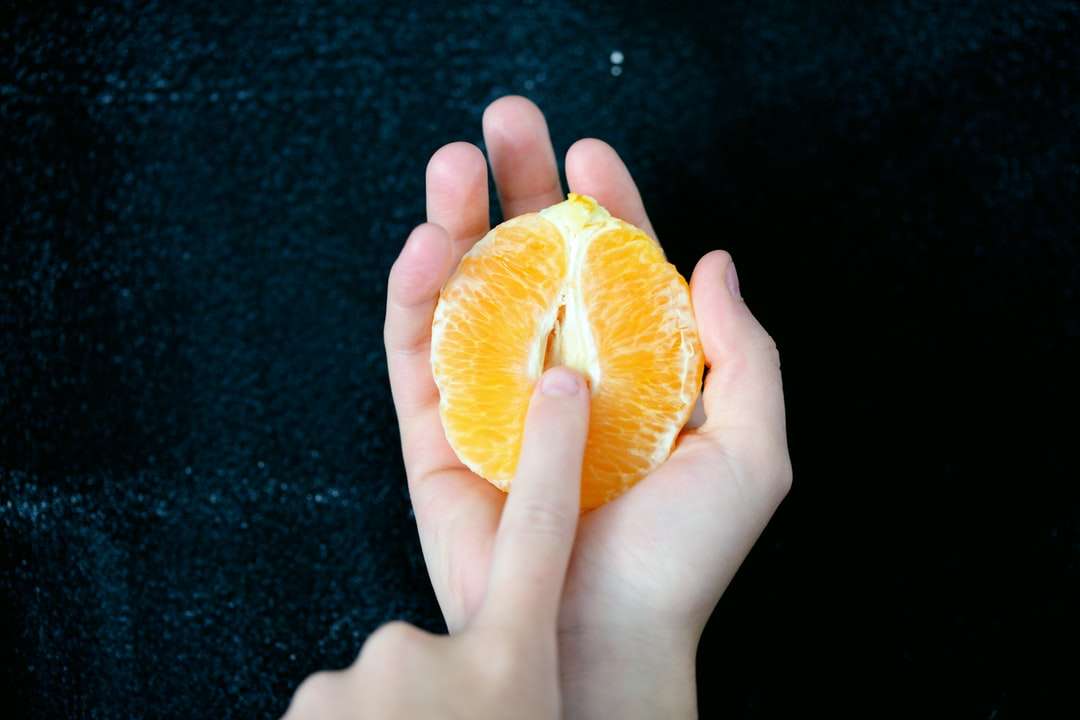 osoba trzymająca pokrojone pomarańczowe owoce puzzle online