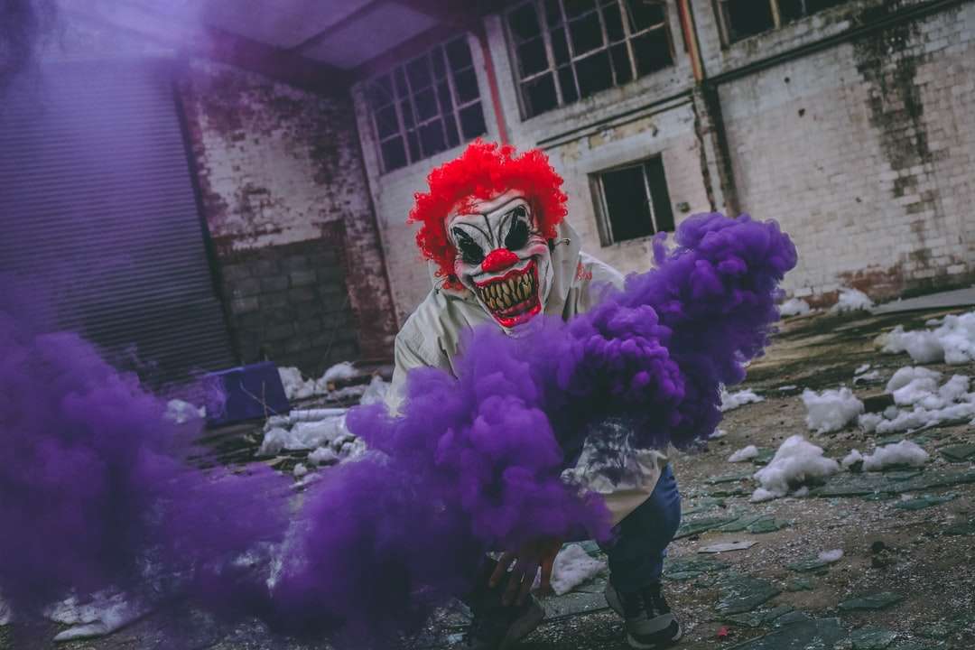 Klaun trzymający fioletową bombę dymną w zrujnowanym budynku puzzle online