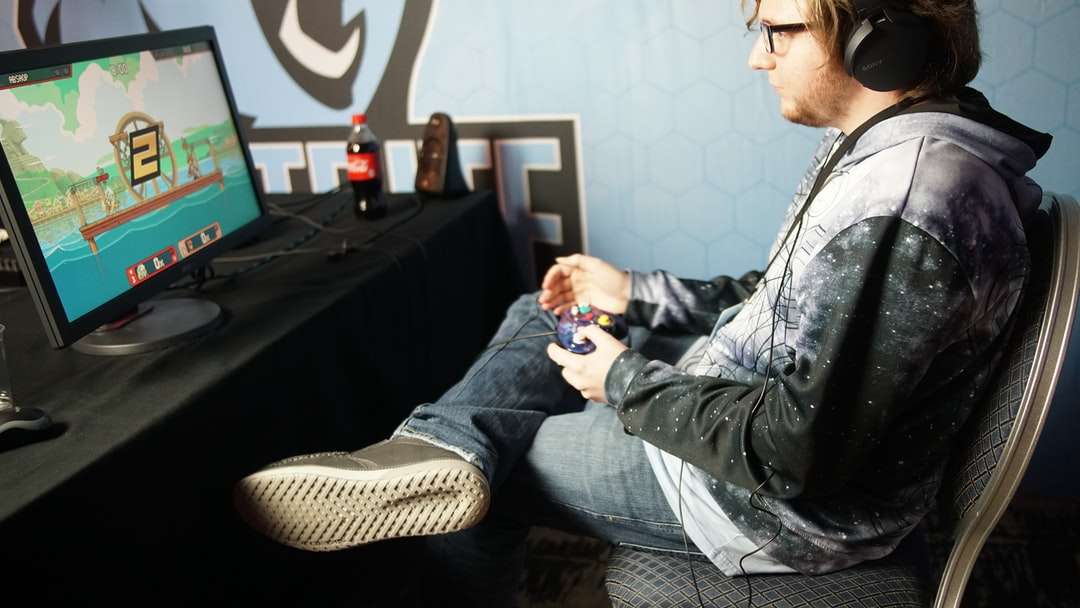 mężczyzna siedzący i grający w gry wideo za pomocą panelu sterowania puzzle online