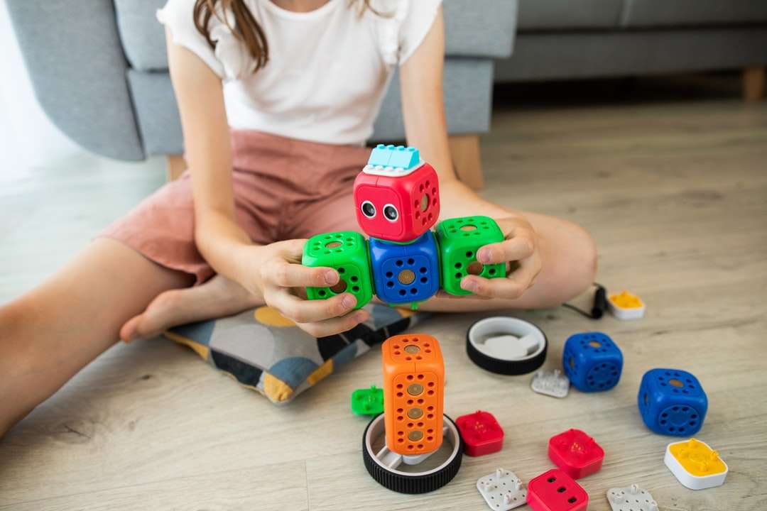 dziewczyna w białej koszuli bawi się niebiesko-czerwoną zabawką samochodową puzzle online