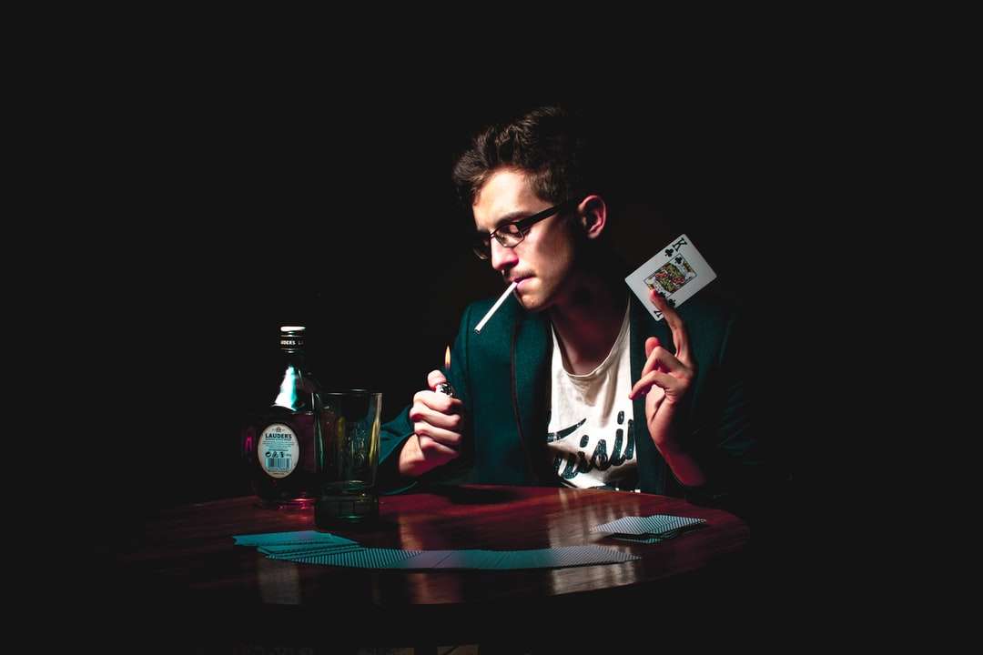 mężczyzna zapala papierosa trzymając kartę do gry puzzle online