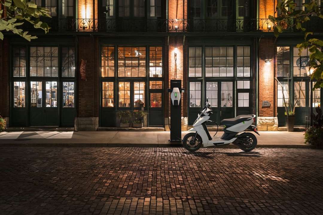 czarno-biały skuter zaparkowany obok brązowego budynku puzzle online