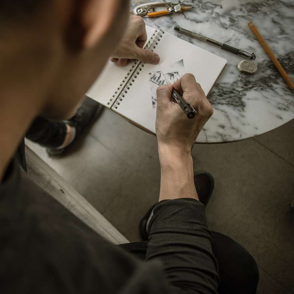 mężczyzna rysujący górę na białym notebooku puzzle online