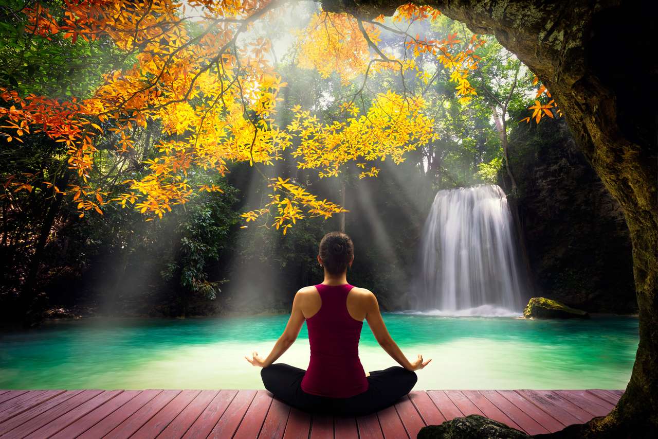 Młoda kobieta w pozie jogi siedząca w pobliżu wodospadu puzzle online