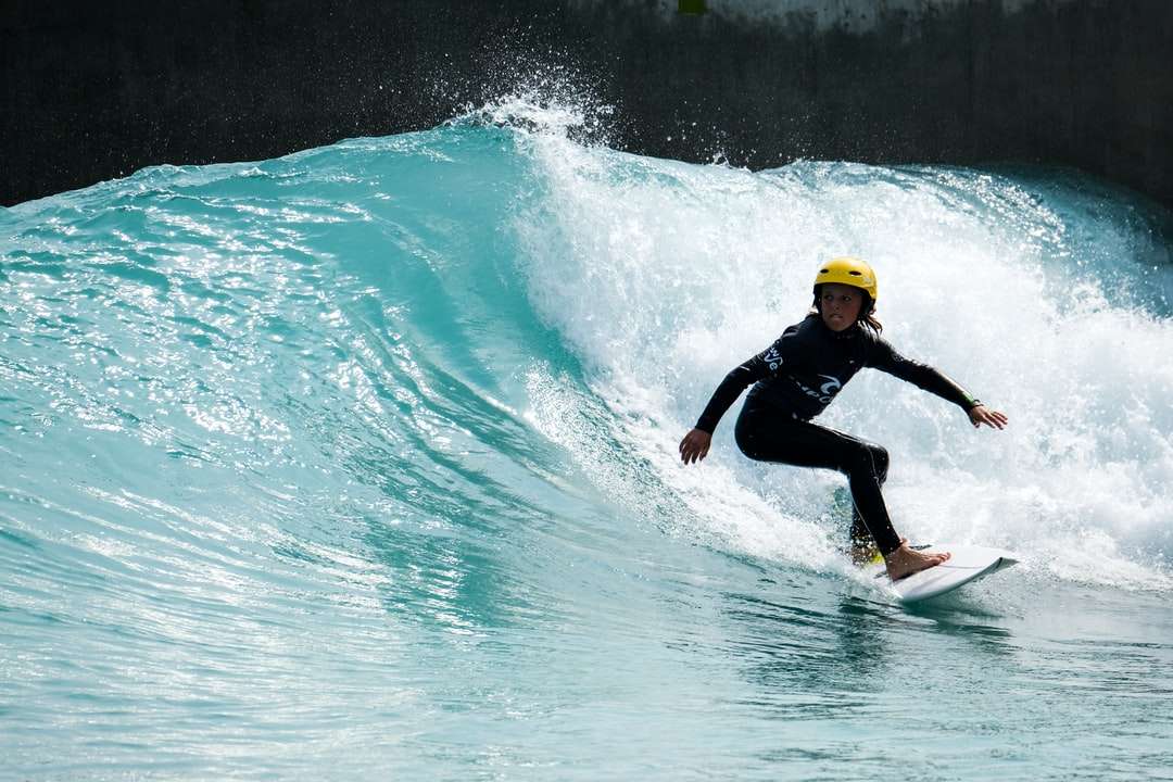 mężczyzna w czarnym kombinezonie pływającym na żółtej desce surfingowej na wodzie puzzle online