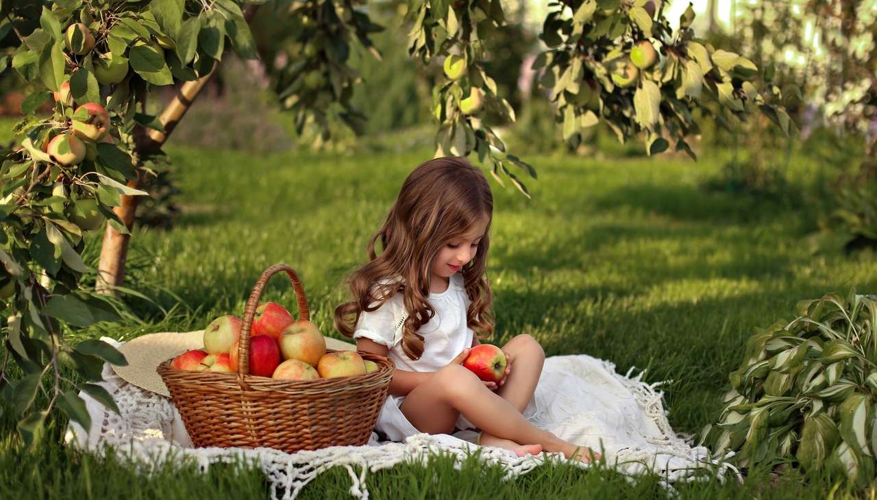 Dziewczynka w letnim sadzie z koszem pełnym jabłek puzzle online