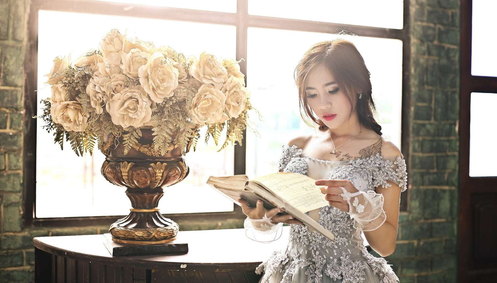 Kobieta z książką obok róż w wazonie przy oknie puzzle online